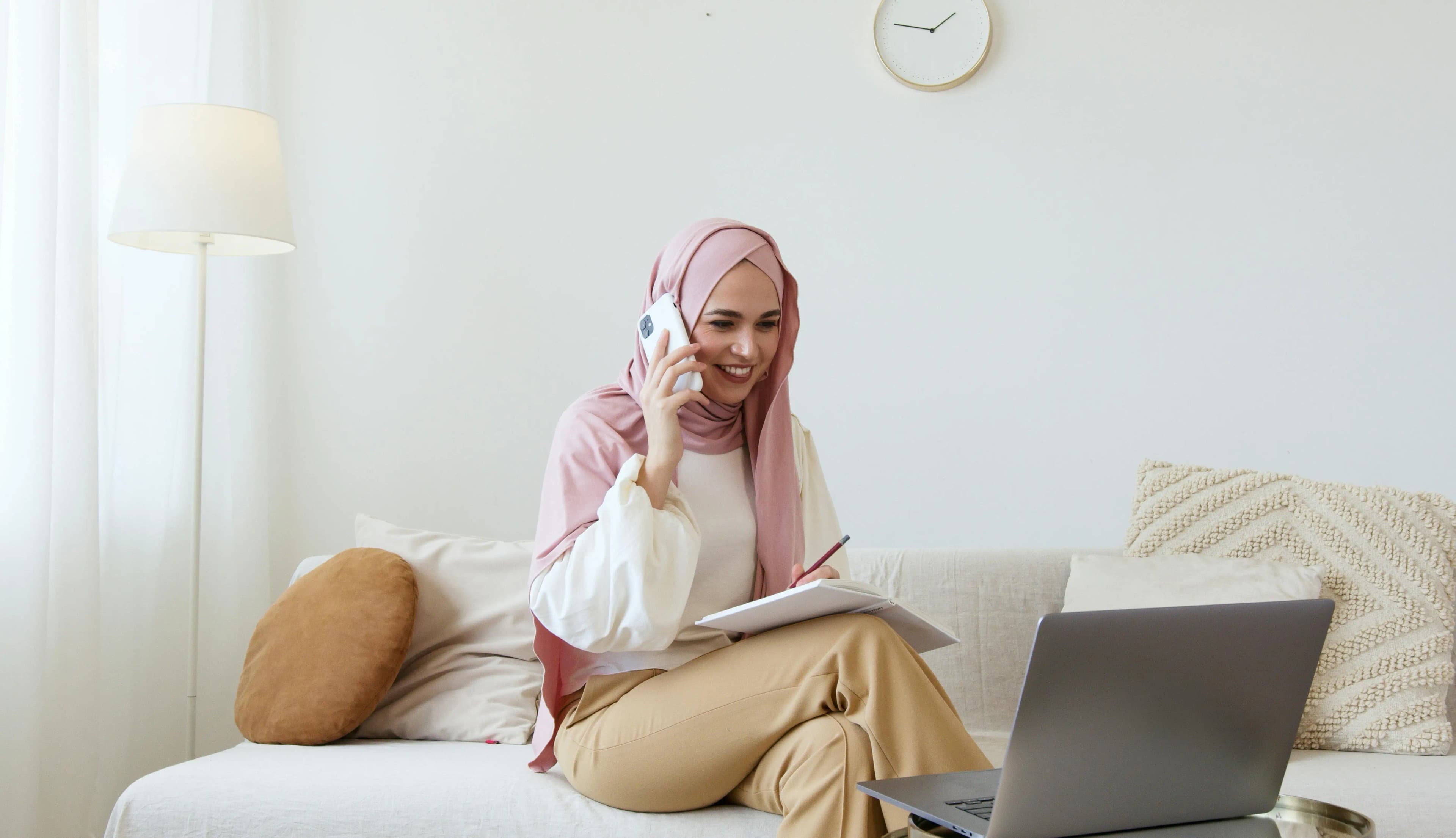 Woman holding a phone and smiling in front of a laptop
